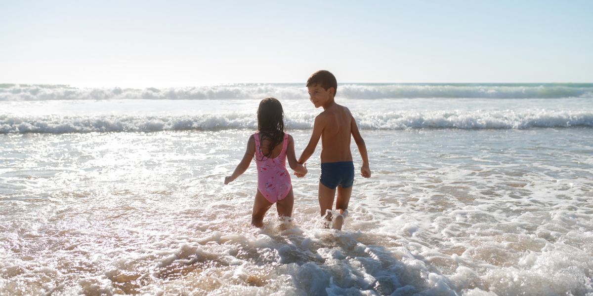 due bambini mano nella mano che camminano verso il mare
